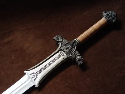 A detailed close-up of an ornate, man-made sword with intricate designs on the blade and a textured handle, set against a rich, dark background, forming an impressive HD desktop wallpaper.