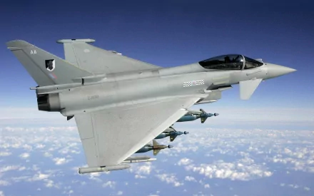 HD desktop wallpaper showing a Eurofighter Typhoon jet soaring above clouds in a clear blue sky, highlighting its sleek military design and armament.