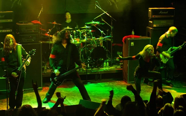 HD PC desktop wallpaper featuring Arch Enemy performing live on stage with green lighting and an energetic crowd in the foreground.