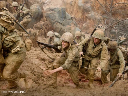 HD PC desktop wallpaper from TV show The Pacific (2010): WWII US Marines in helmets and packs scrambling up a muddy, rocky beach amid smoke and chaos.