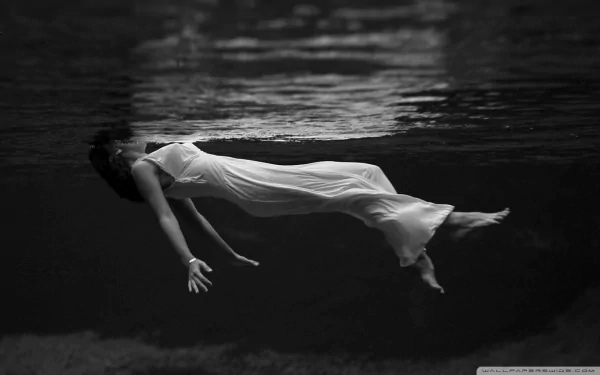 A serene black and white photograph of a woman in a flowing white dress, gracefully submerged in water, creating a captivating and tranquil HD desktop wallpaper.