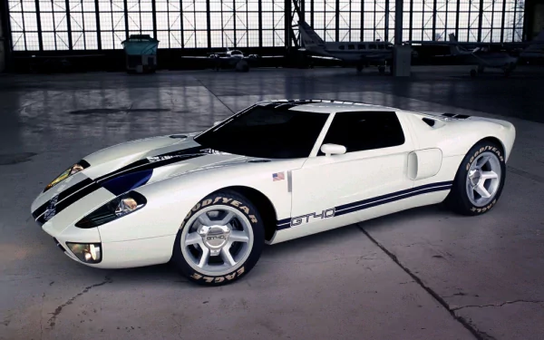 HD PC desktop wallpaper featuring a sleek white Ford GT40 sports car parked inside a spacious industrial garage with large windows in the background.