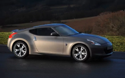 Silver Nissan sports coupe parked on a wet road against rolling hills at dusk — HD PC desktop wallpaper/background.