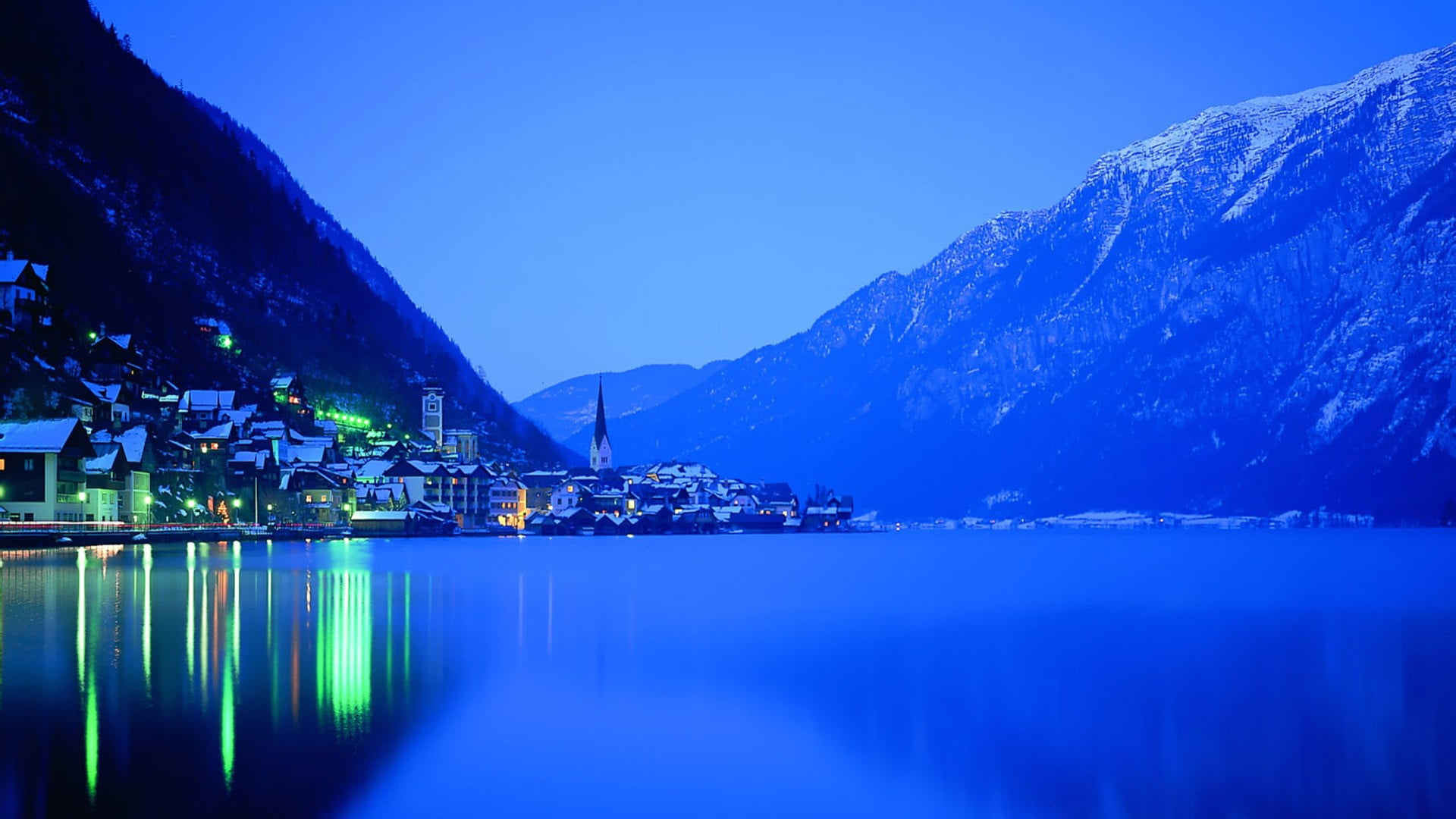 Night view of a village nestled by a lake surrounded by mountains in Hallstatt, Austria.