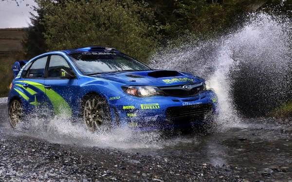 HD PC desktop wallpaper featuring a blue Subaru vehicle splashing through water on a rugged, natural terrain.