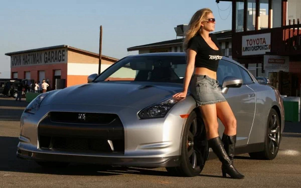4K Ultra HD wallpaper featuring a sleek silver Nissan sports car with a woman leaning against it in an urban garage setting.