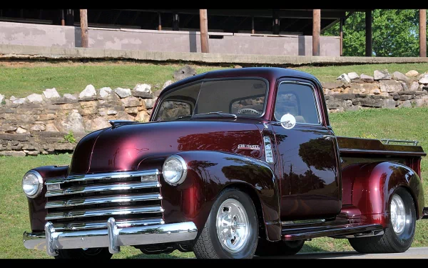 Glossy maroon Chevrolet vintage pickup parked on grass in front of a stone wall — 4K Ultra HD PC desktop wallpaper/background.