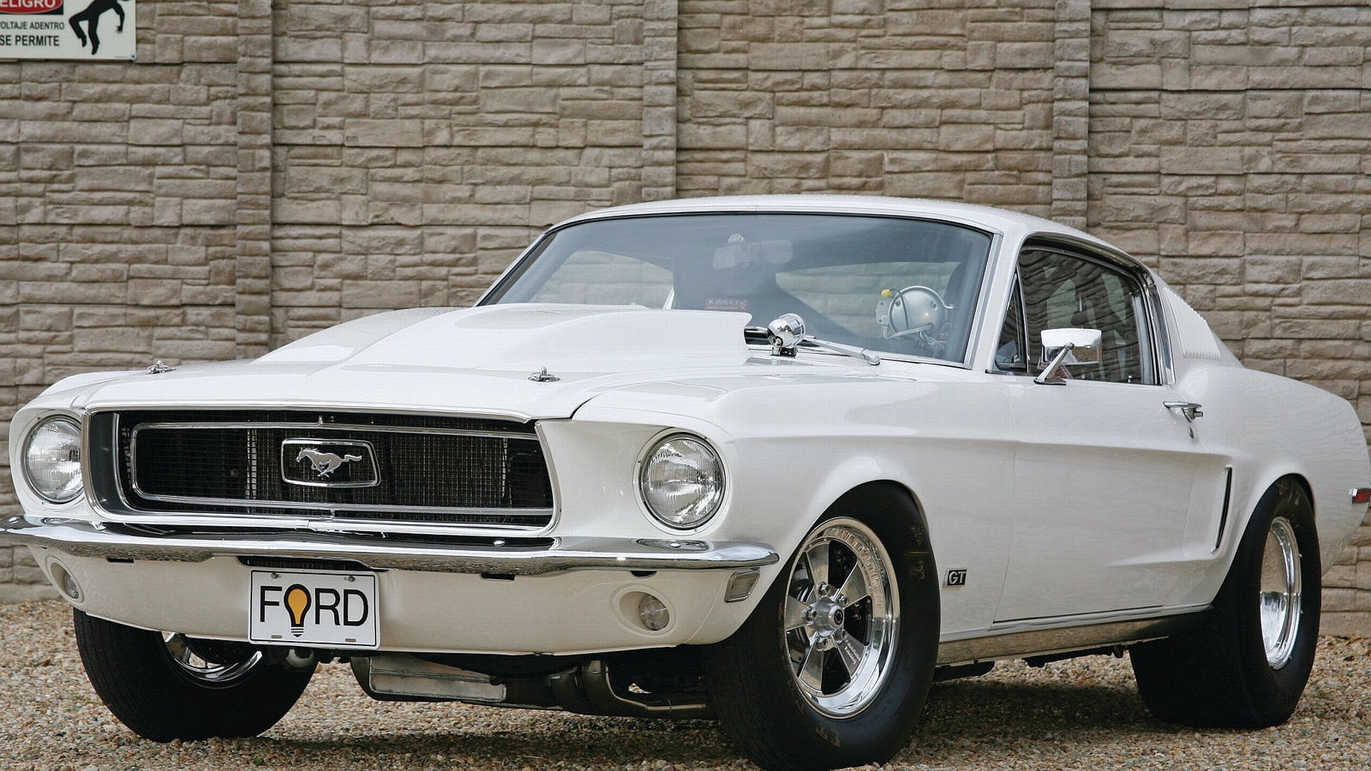 HD desktop wallpaper featuring a classic white Ford Mustang parked in front of a brick wall, showcasing the iconic vehicle in sharp detail.