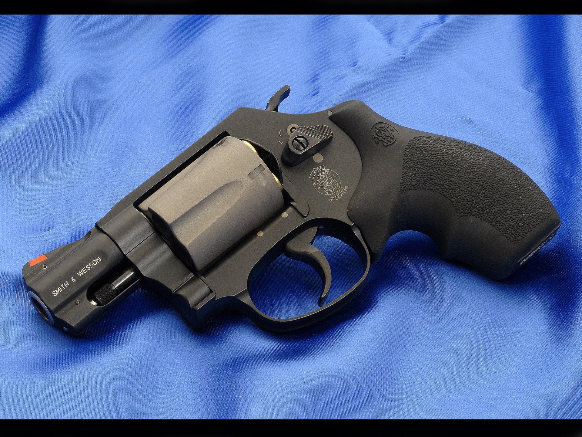 HD desktop wallpaper featuring a close-up of a Smith & Wesson revolver resting on a blue fabric background.