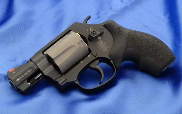 HD desktop wallpaper featuring a close-up of a Smith & Wesson revolver resting on a blue fabric background.