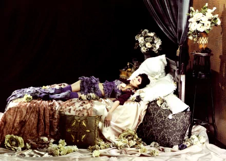 A captivating HD wallpaper featuring Mika Nakashima, lying gracefully on a bed adorned with lush fabrics and surrounded by elegant floral arrangements.