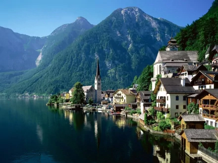 HD desktop wallpaper of Hallstatt featuring a serene town by a lake with charming, man-made buildings, set against a backdrop of majestic mountains.