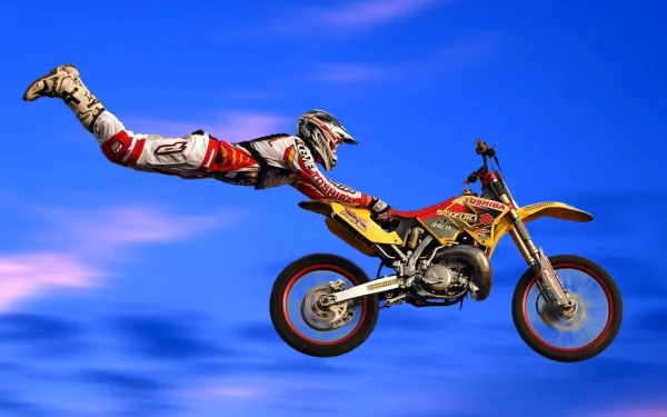 A motocross rider performing a mid-air stunt on a yellow motorcycle against a vivid blue sky, captured in HD for a dynamic sports desktop wallpaper and background.
