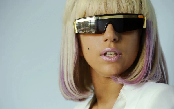 4K Ultra HD PC desktop wallpaper: close-up portrait of a music artist with a platinum bob, gold visor sunglasses, pale pink lips and purple-tipped strands, wearing a sleek white blazer.