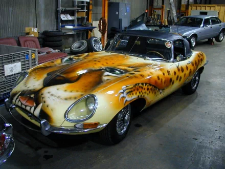 Custom-painted Jaguar E-Type with a snarling leopard head livery parked in a garage — modified classic sports car, HD PC desktop wallpaper
