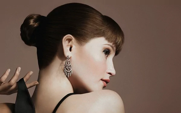 Elegant HD wallpaper featuring Gemma Arterton, showcasing her profile with a stylish updo and statement earrings against a soft, neutral backdrop.