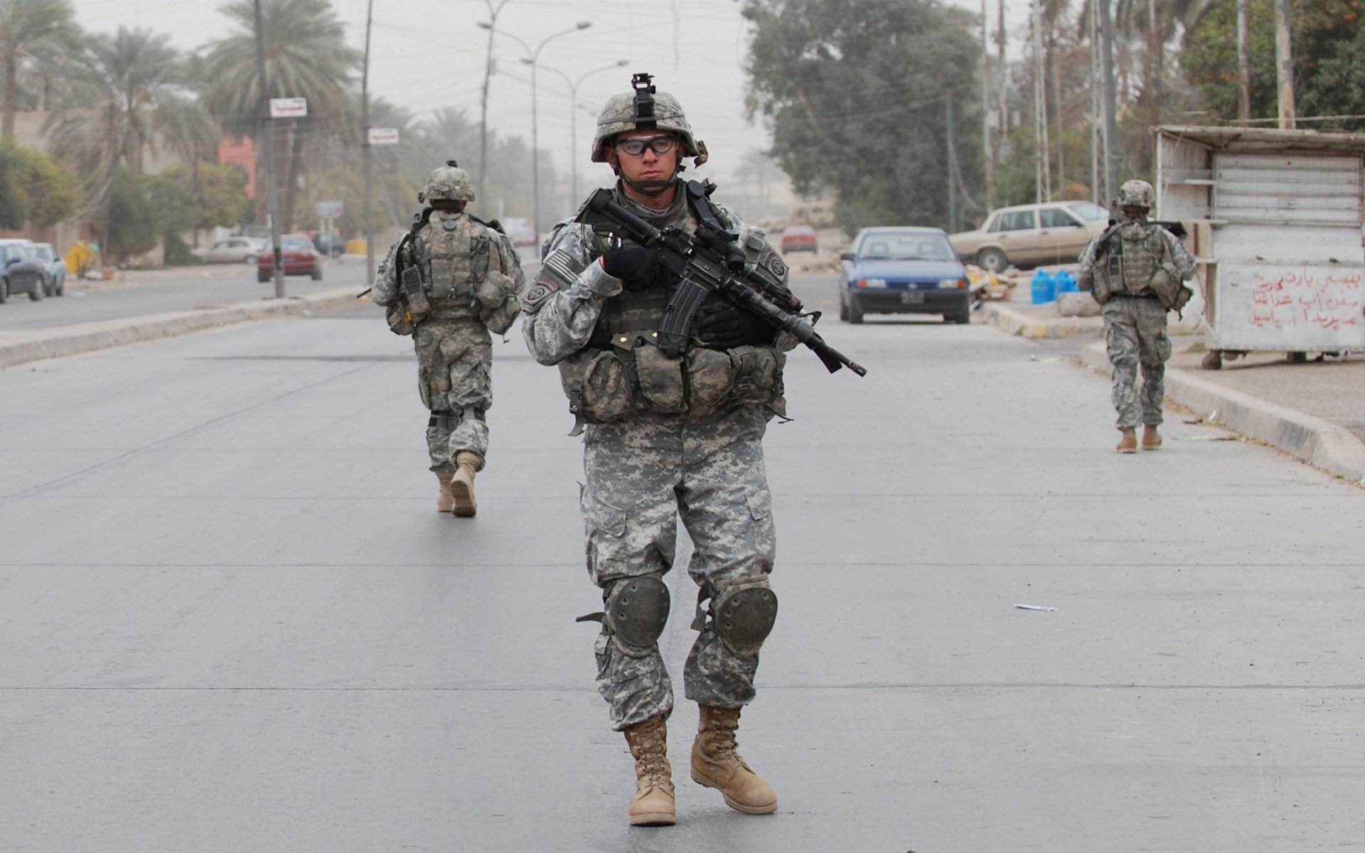 U.S. Army Infantry soldiers armed and patrolling a street in a war zone, captured in high definition for a military-themed desktop wallpaper.