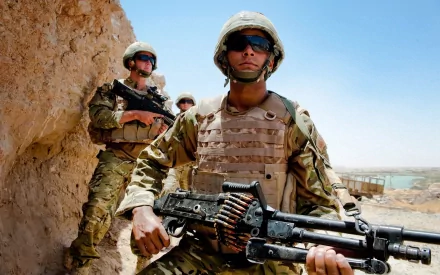 U.S. Army Infantry soldiers in combat gear holding weapons in a desert setting, representing military service and warfare.
