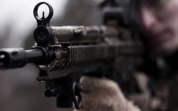 Close-up of a soldier aiming a Heckler & Koch MP5 rifle, showcasing the military-grade weapon in sharp focus against a blurred background.
