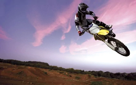 A motocross rider performs an air maneuver against a vibrant sky, capturing the thrill of the sport. This HD image serves as a dynamic desktop wallpaper and background.