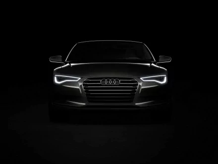 HD PC desktop wallpaper and background showing the front of an Audi vehicle with glowing LED headlights and grille emerging from deep black.