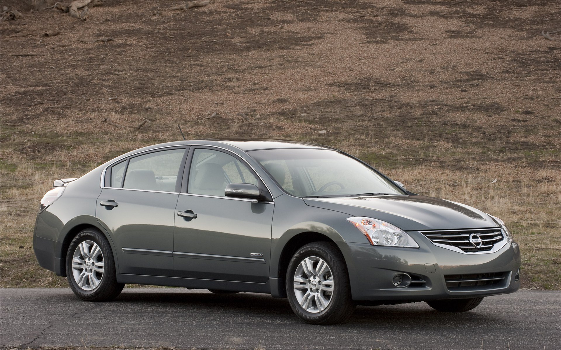 HD PC desktop wallpaper of a gray Nissan Altima sedan parked by a grassy hillside, the Nissan vehicle shown in profile as a clean background image.