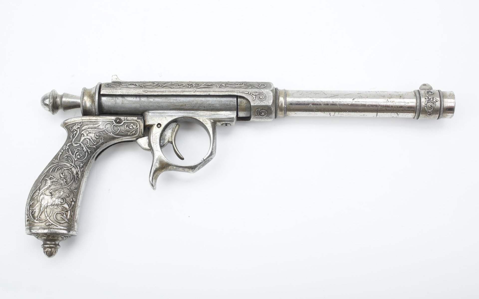 A detailed, silver antique pistol with intricate engravings, showcased against a clean background. This HD wallpaper captures the craftsmanship of man-made weaponry.