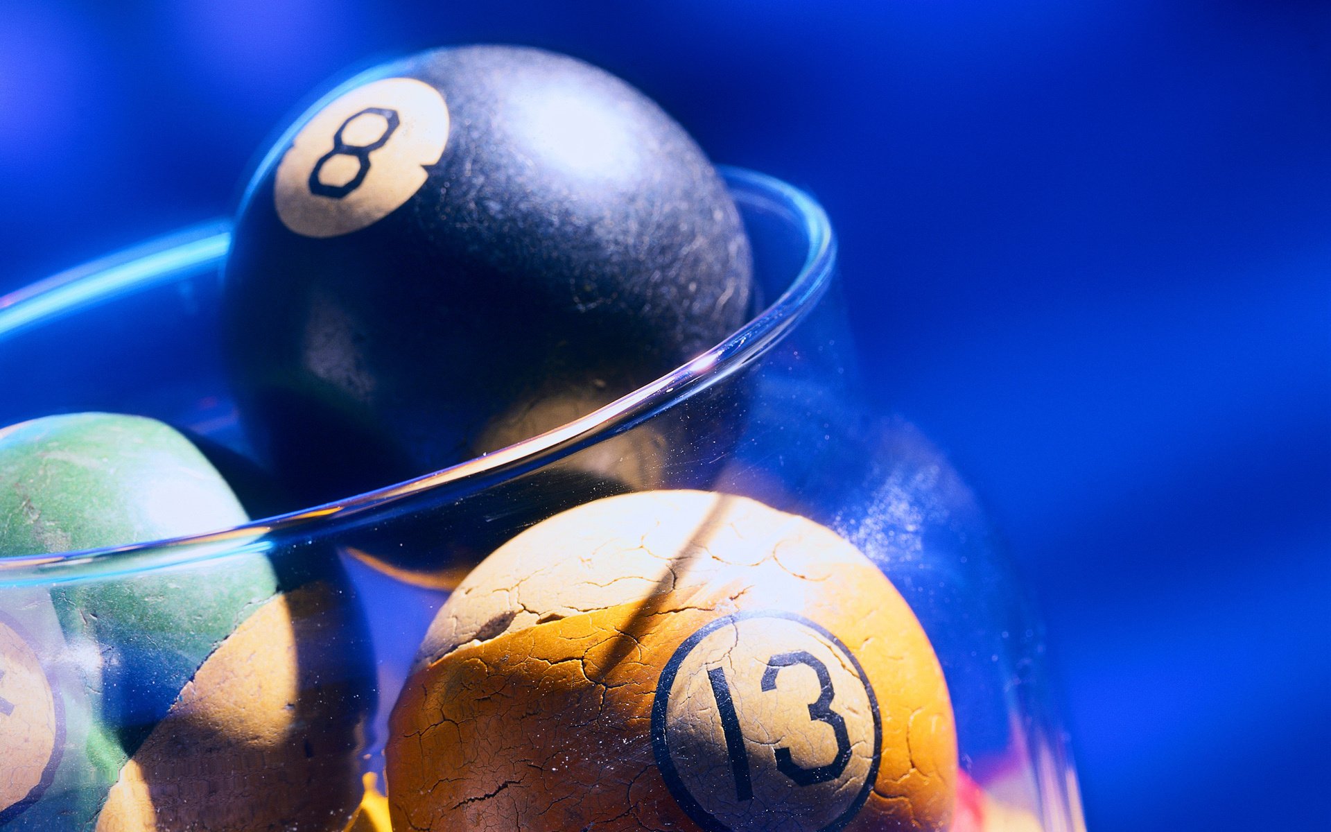A close-up of pool balls, including the 8 and 13, in a clear glass bowl against a blue background, designed as HD PC desktop wallpaper and background.
