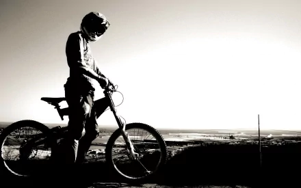 Monochrome HD desktop wallpaper featuring a BMX rider in a helmet and gear, standing with a BMX bike against a scenic backdrop.
