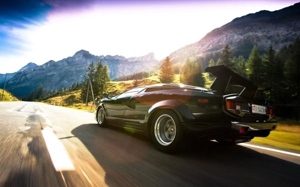 A sleek black Lamborghini Countach drives along a picturesque mountain road, bathed in golden sunlight, showcasing its iconic design against a stunning natural backdrop.
