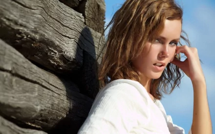 HD PC desktop wallpaper featuring celebrity Thora Birch posing outdoors against rustic wooden beams under a clear blue sky.