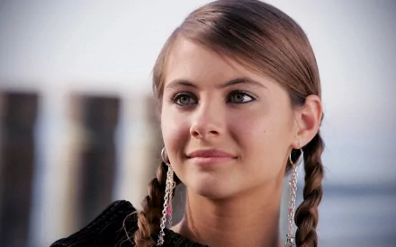 HD desktop wallpaper featuring Willa Holland, showcasing her with braided hair and hoop earrings against a scenic background.