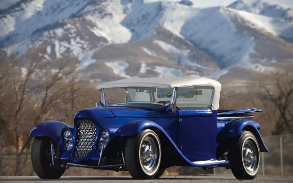 A vintage blue Ford vehicle parked outdoors with snow-capped mountains in the background, featured as an HD PC desktop wallpaper and background.