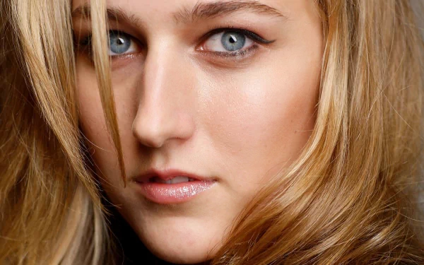A close-up portrait of a woman with striking blue eyes and wavy blonde hair, serving as a HD PC desktop wallpaper and background.
