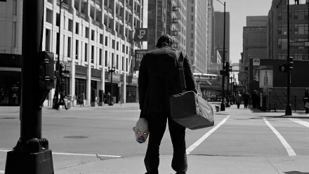 HD PC desktop wallpaper from the movie The Dark Knight, featuring a man in a suit holding a white mask, standing on a city street in a grayscale urban setting.