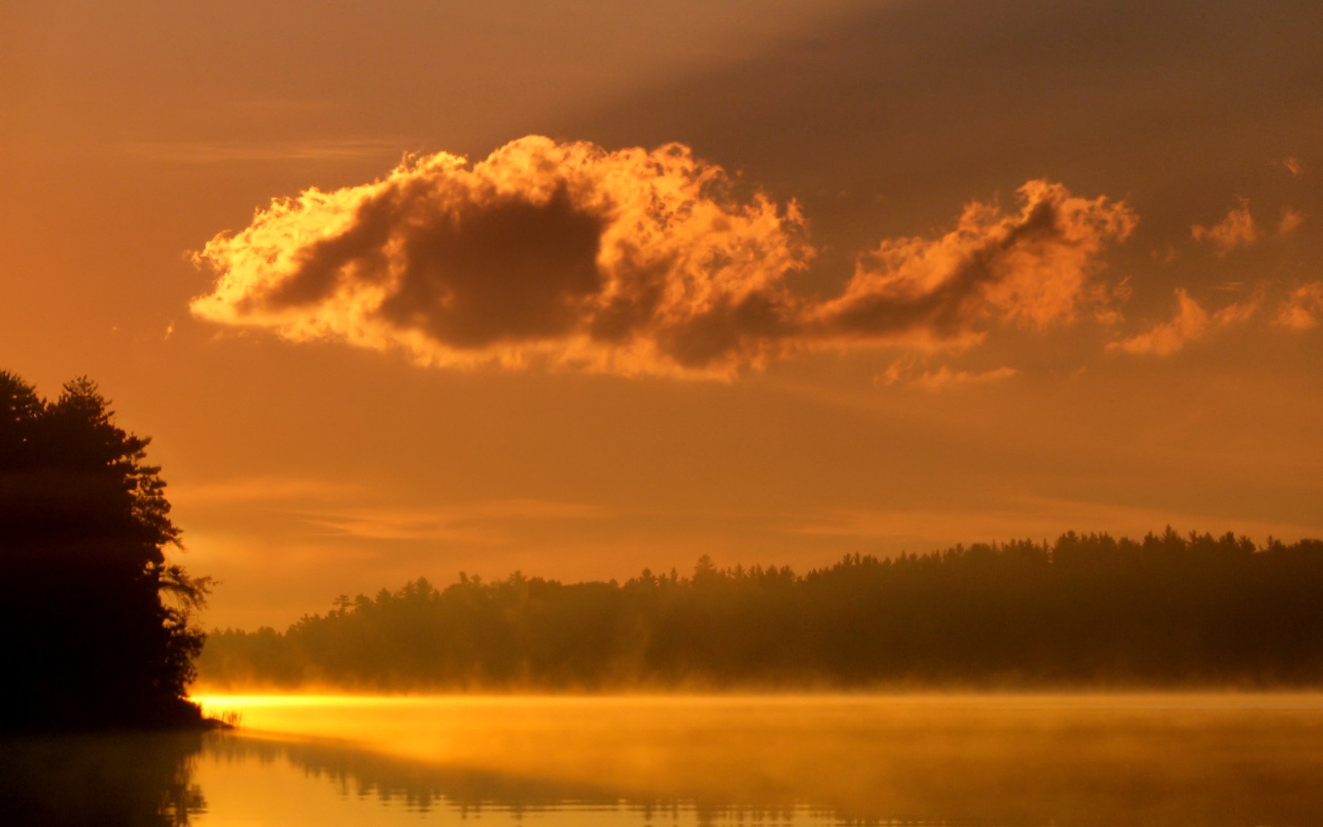 HD PC desktop wallpaper capturing a serene nature scene with fog over calm water and a glowing orange sky during sunrise or sunset.