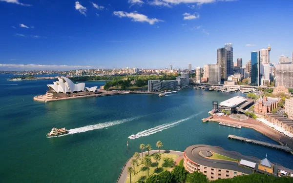 Aerial view of Sydney Harbour featuring the Sydney Opera House, Circular Quay, and city skyline under a clear blue sky in Australia.