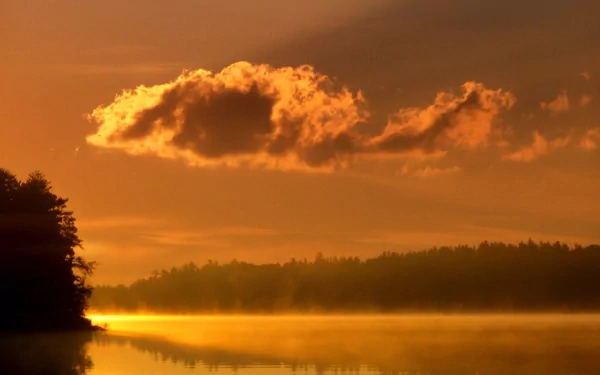 HD PC desktop wallpaper capturing a serene nature scene with fog over calm water and a glowing orange sky during sunrise or sunset.