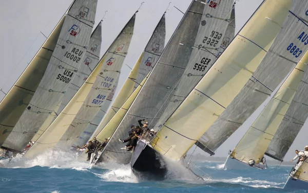 HD PC desktop wallpaper background of racing sailboats (vehicle, boat) heeling sharply, crews on deck with bows cutting through blue water and spray flying.