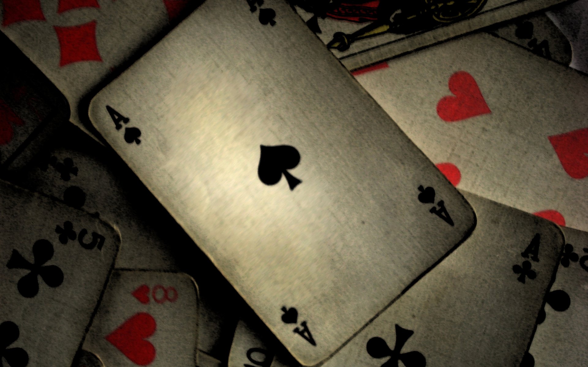 A high-definition desktop wallpaper featuring a close-up of playing cards, prominently displaying an Ace of Spades among scattered cards with various suits.