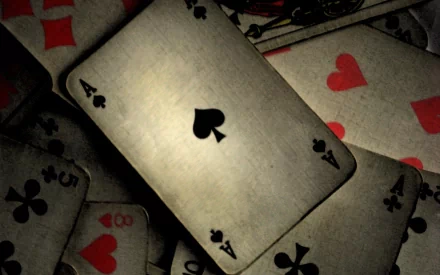 A high-definition desktop wallpaper featuring a close-up of playing cards, prominently displaying an Ace of Spades among scattered cards with various suits.