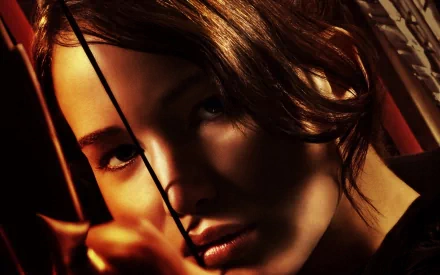 Close-up HD desktop wallpaper of Jennifer Lawrence as Katniss Everdeen from the movie The Hunger Games, highlighting her intense expression with a bow in hand.