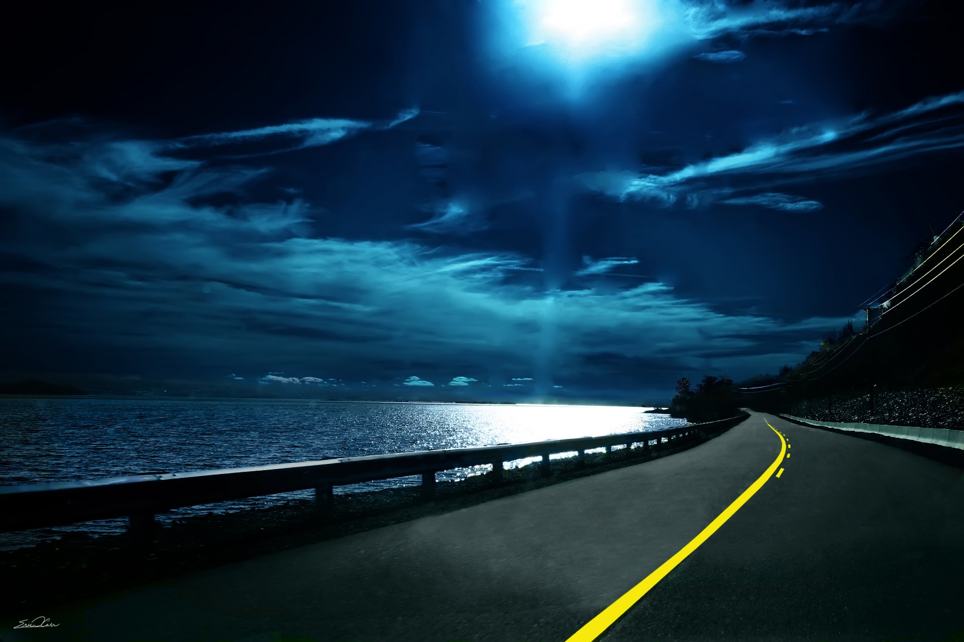A stunning HD desktop wallpaper featuring a man-made road curving along a body of water under a dramatic cloudy sky illuminated by the moon.