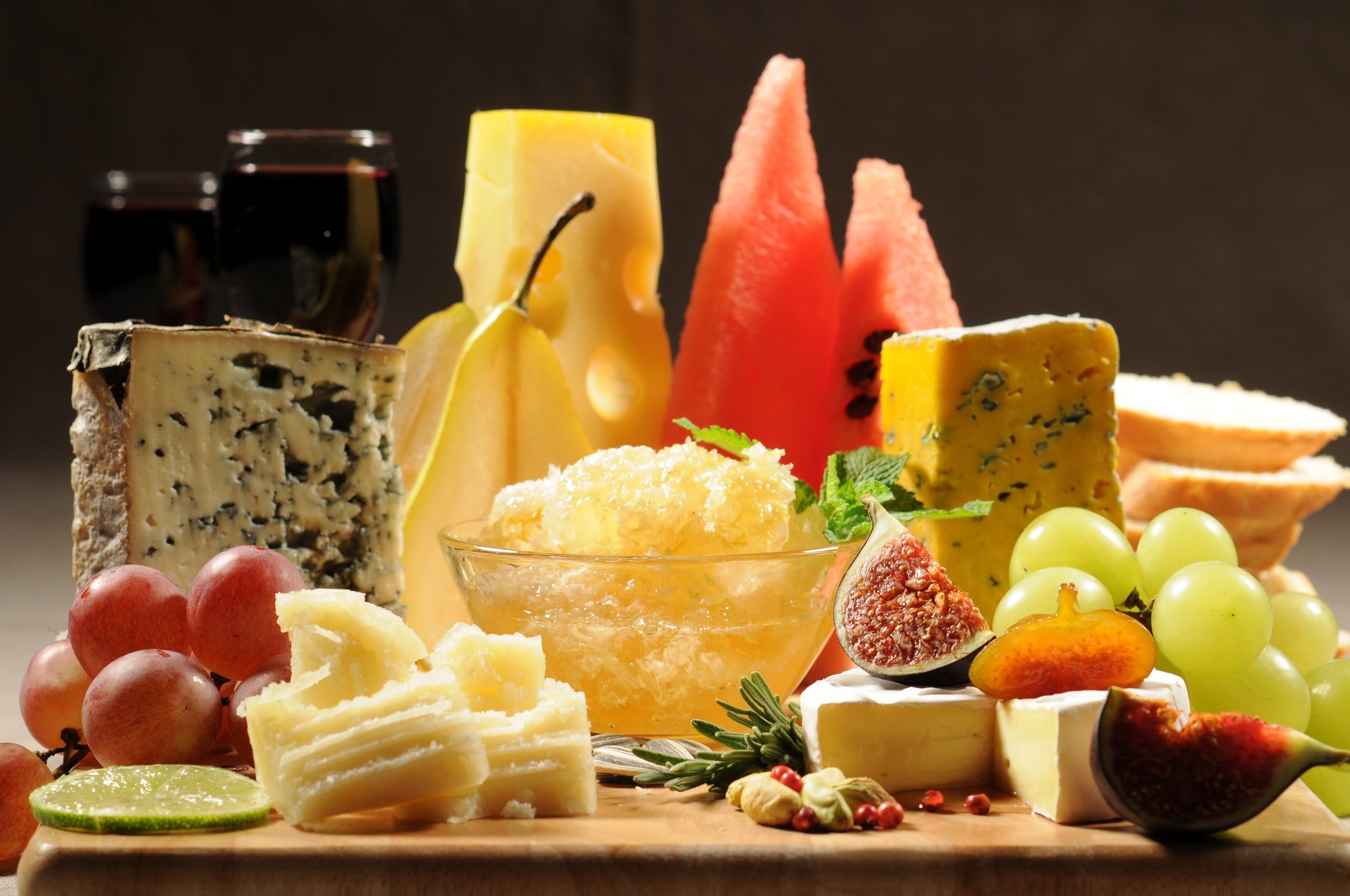 Food still life 4K Ultra HD PC desktop wallpaper and background of assorted cheeses, melon, figs, grapes and preserves arranged on a dark surface.