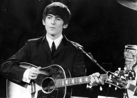 A black and white HD wallpaper featuring George Harrison of The Beatles, performing with an acoustic guitar, capturing the essence of 1960s music.