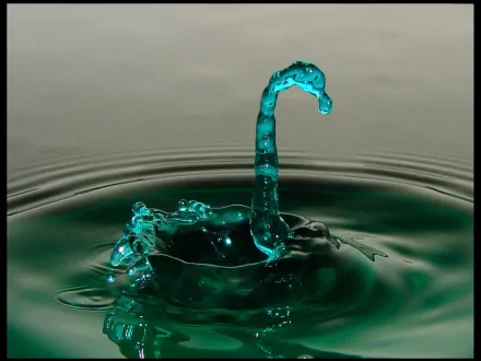 An artistic HD wallpaper featuring a striking water splash with a fluid, turquoise shape emerging from the surface, creating a captivating visual effect.