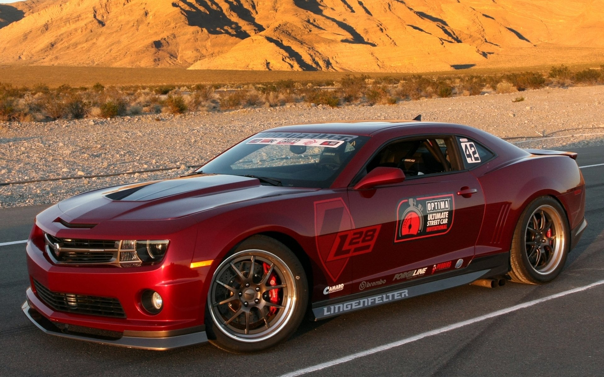 Red Chevrolet Camaro sports car on a desert road at sunset — HD PC desktop wallpaper and background with racing decals and alloy wheels.