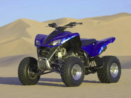 HD PC desktop wallpaper of a blue ATV vehicle parked on sandy desert terrain with dunes in the background.