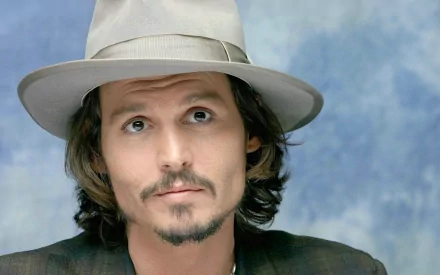High-definition PC desktop wallpaper featuring Johnny Depp, showcasing the actor in a stylish hat against a soft blue background, capturing his charismatic presence.