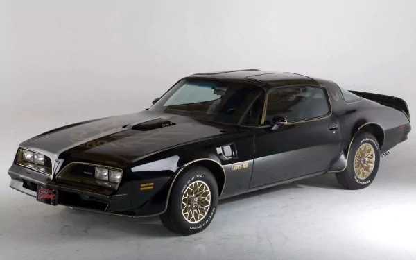 Black Pontiac vehicle (Trans Am) in studio on a neutral backdrop — HD PC desktop wallpaper and background showcasing its sleek muscle-car profile and gold wheels.